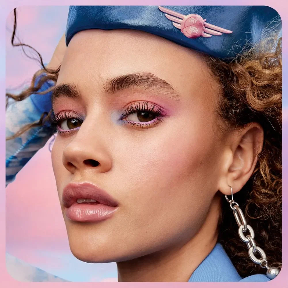 Primer plano de mujer con maquillaje colorido, pestañas largas y gorra azul, Somos Lashy